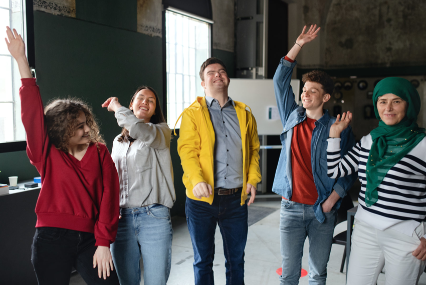 Diverse group of young people with hands raised, smiling, enjoying NDIS Community Access