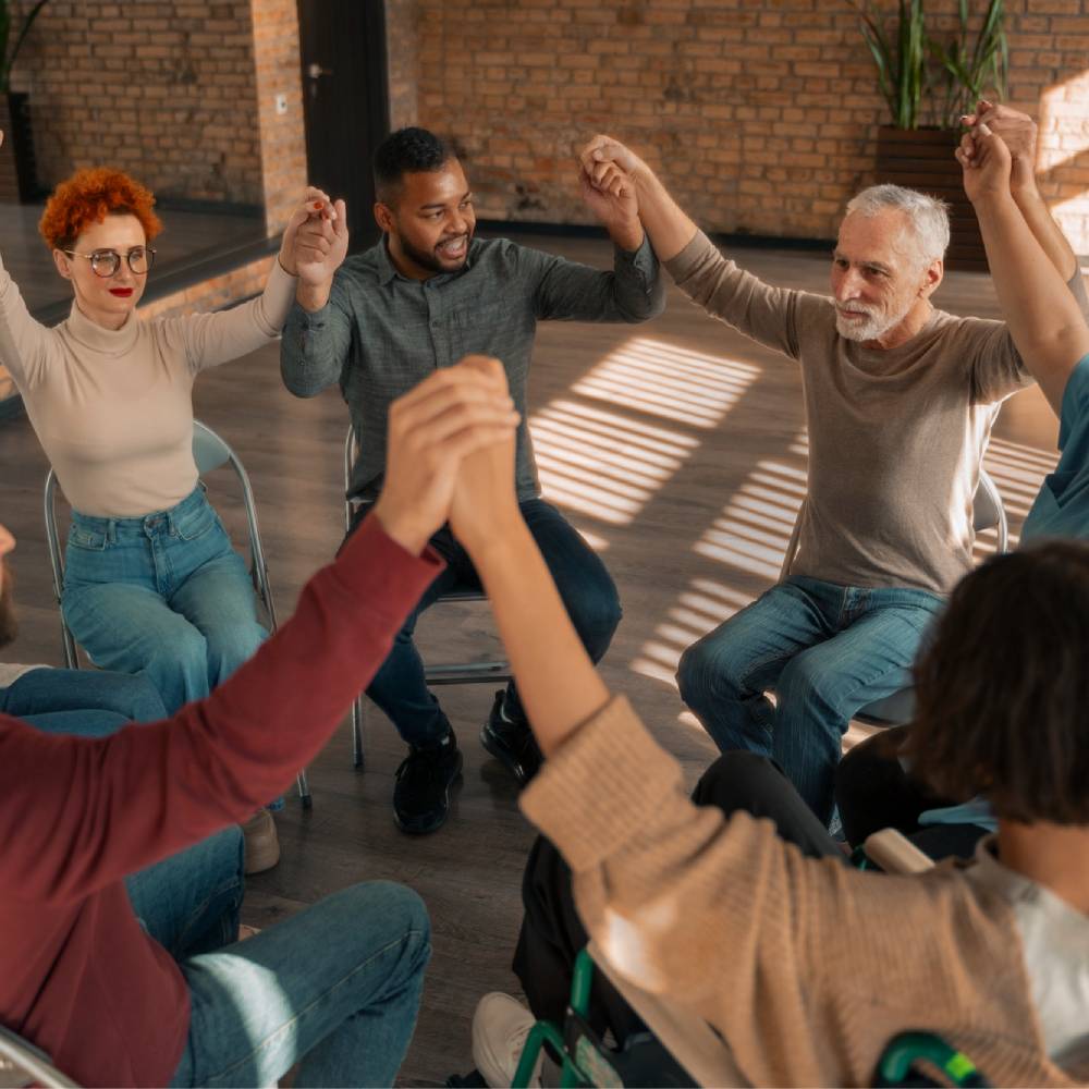 Diverse group in a circle, holding hands, benefiting from NDIS Community Access & Support