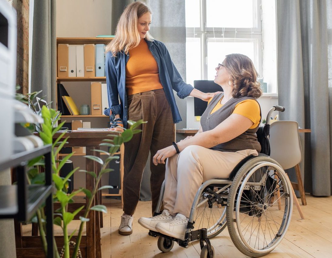 Support worker talking with woman in wheelchair at home office - Support Coordination