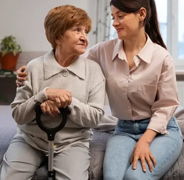 Caring support worker with arm around senior woman with walking stick